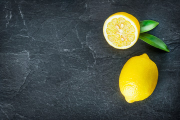 Fresh lemons on dark stone table. Ripe lemon from top view with green leaves. Fresh ripe lepon...