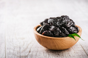 Prunes in wooden bowl on old rustic table. dried plums on table. Heap of prunes on old board.
