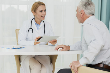 Doctor talking to patient while holding tablet