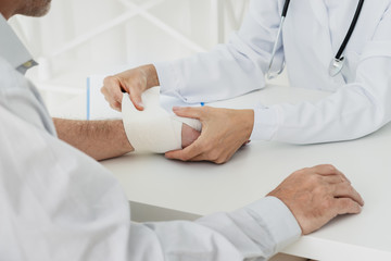 Doctor bandaging hand of patient