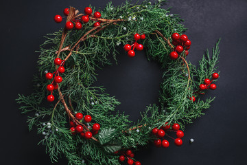 Fototapeta na wymiar Christmas wreath detail of evergreen and berries on dark background.