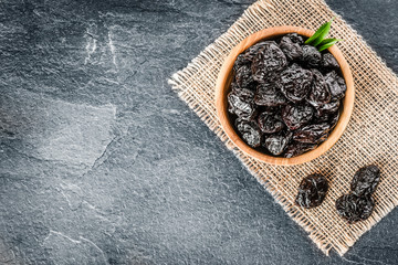 Fresh prunes in wooden bowl. Prunes on stone dark table. Prunes healthy food. Dried plums.