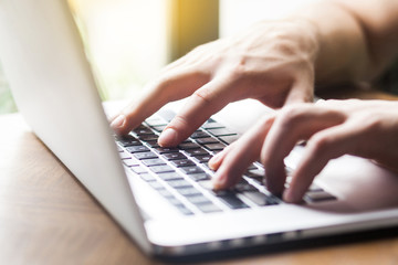 CLoseup of human hand typing on laptop keyboard. Young businessman sitting and working on laptop....