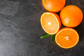 Fresh oranges on dark stone table. Half oranges on table from top view. Tasty oranges fruits.