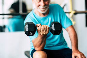 adult man and mature senior at the gym working his body with dumbbell - one man hapy training...
