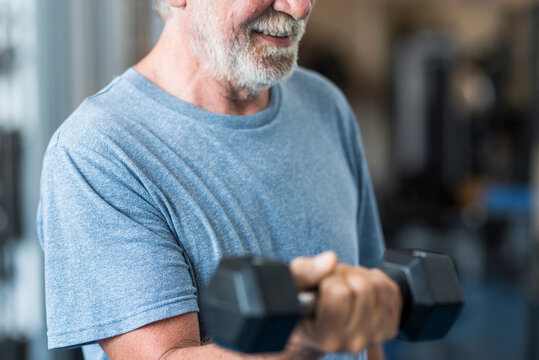 adult man and mature senior at the gym working his body with dumbbell - one man hapy training indoors