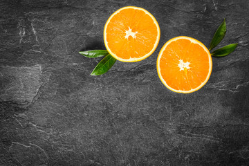 Fresh ripe tasty oranges on stone table. Orange on black background. Cut half oranges from top view.