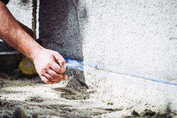 Main d'un homme en train de marquer le niveau au cordeau