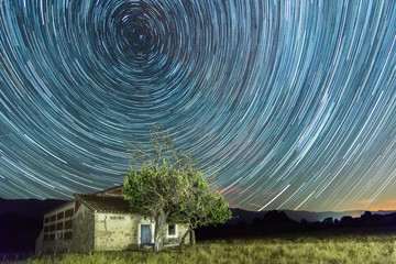 Star trails with shooting stars on a country house