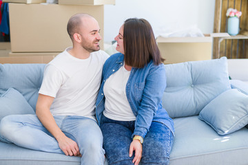 Young couple in love relaxing and hugging sitting on the sofa at new home, smiling very happy for moving to a new apartment