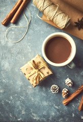 Obraz na płótnie Canvas Mug of hot chocolate, spices, gift box and wrapping paper on gray background. Christmas template. Flat lay
