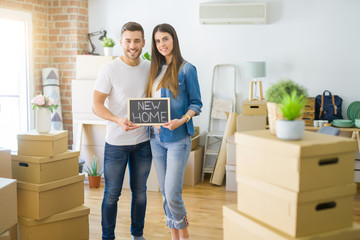 Fototapeta na wymiar Young beautiful couple holding blackboard with new home text at new house with a happy face standing and smiling with a confident smile showing teeth