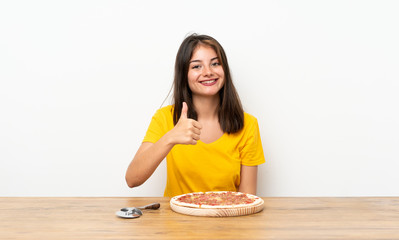 Caucasian girl with a pizza giving a thumbs up gesture