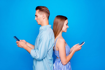 Profile side view portrait of his he her she two nice attractive focused cheerful cheery people using device chatting isolated over bright vivid shine vibrant blue color background