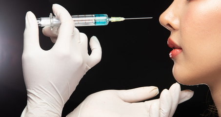 Beautician Plastic Surgery Doctor Nurse in Hygiene glove injects syringe with beautiful serum to...