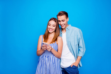 Portrait of his he her she two nice attractive lovely charming cheerful cheery people using cell browsing media share isolated on bright vivid shine vibrant blue color background