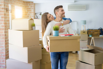 Beautiful young couple moving to a new house, smiling happy holding cardboard boxes at new apartment