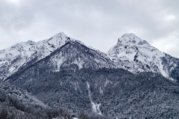 Two mountain peaks in the snow under gloomy clouds