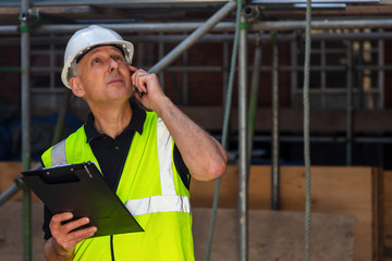 Worried Male Builder Architect Contractor on Building Site Using Phone