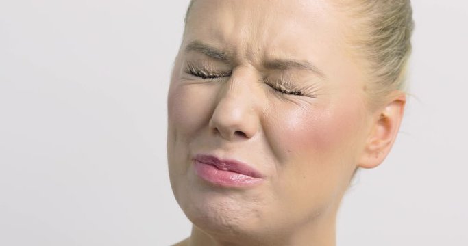 Close-up of a pretty blonde woman eating a sour berry and making faces.