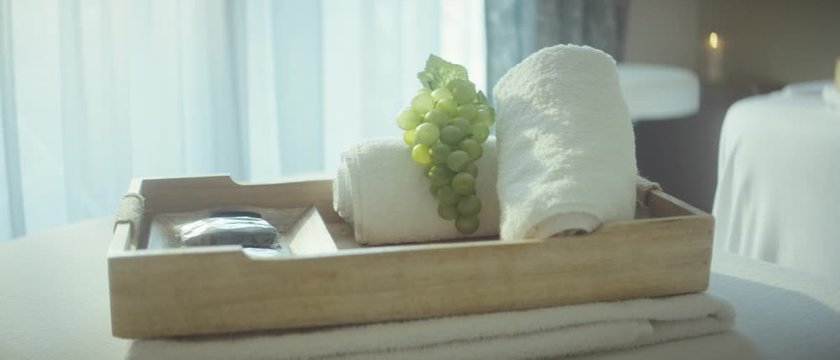 a wooden tray with towels and grapes on top of a massage couch in a luxurious spa - Ein h&ouml;lzernes Tablett mit Handt&uuml;chern und Trauben auf einer Massageliege in einem luxori&ouml;sen Wellnessetablisment