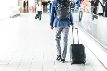 Man pulling his suitcase on airport station near escalator.