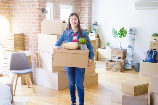 Beautiful asian young woman holding boxes, smiling happy moving to a new home