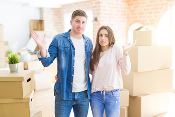 Fototapeta na wymiar Beautiful young couple moving to a new house clueless and confused expression with arms and hands raised. Doubt concept.