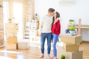 Fototapeta na wymiar Beautiful young couple moving to a new home, standing on new aparment around cardboard boxes, hugging smiling happy and in love