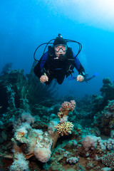 Naklejka na ściany i meble Scuba Diver explores coral reef .
