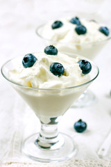 Diet yogurt with large fresh blueberries. White unsweetened yogurt in a glass