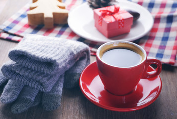 Red coffee cup and glay glove on the table with christmas gift on background