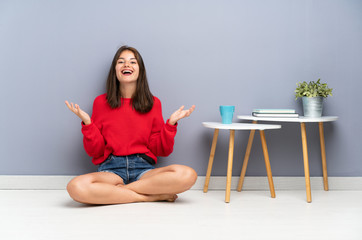 Young woman sitting on the floor unhappy and frustrated with something