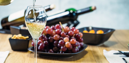 Pouring wine into glass and food background