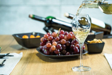 Pouring wine into glass and food background