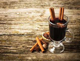 Christmas mulled wine in glass cup on a wooden table. Top view.