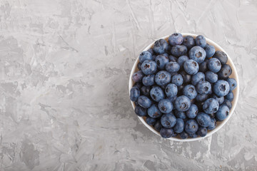 Fresh blueberry in white bowl on gray concrete background. top view.