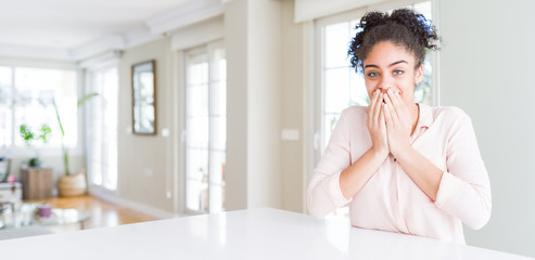 Wide angle of beautiful african american woman with afro hair laughing and embarrassed giggle...