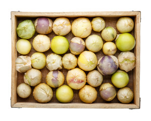 Ripe tomatillo (Mexican husk tomato, Physalis philadelphica, Vegetable physalis) in wooden tray isolated on white. Top view.