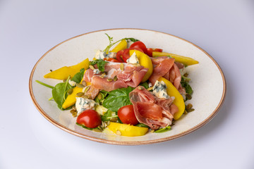 mix salad with ham, blue cheese, tomato, sunflower seeds and mango on white plate.