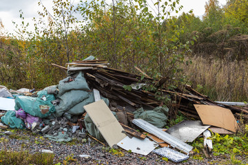 The unauthorized dump of garbage among the wild nature near the industrial and living areas