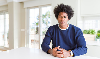 Young african american man wearing casual sweater sitting at home depressed and worry for distress,...