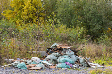 The unauthorized dump of garbage among the wild nature near the industrial and living areas