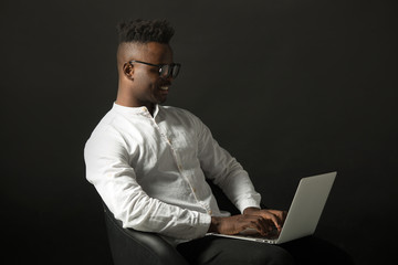 handsome african man in glasses with laptop on black background