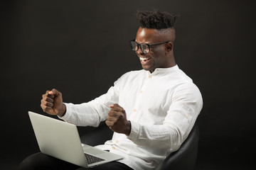 handsome african man in glasses with laptop on black background