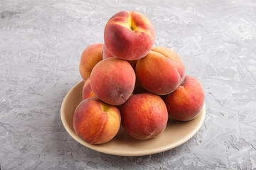 Fresh peaches on a plate on gray concrete background. side view.