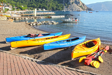 Multi-colored kayaks with oars on the seashore.