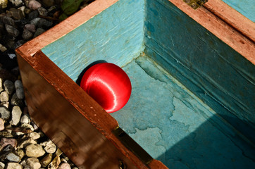 A wooden box with a red shining bullet, christmas bauble in it.