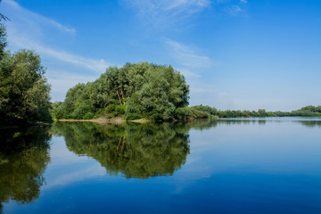 Blue beautiful sky against the background of the river. Clouds are displayed in calm water. On the horizon, the green bank of the Dniester, place for fishing
