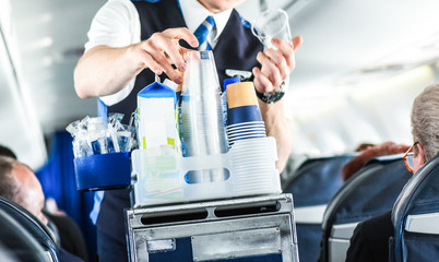 The steward serving glass of water for passengers on board.